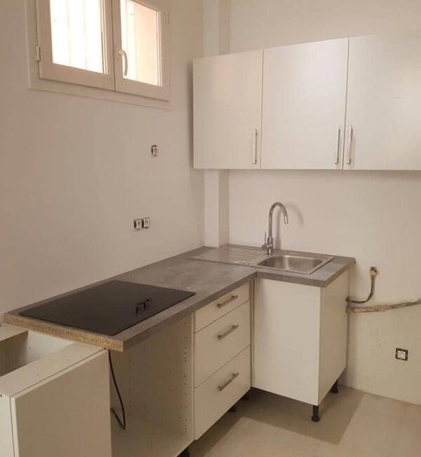 Cocina lineal moderna y luminosa integrada con salón en Barcelona